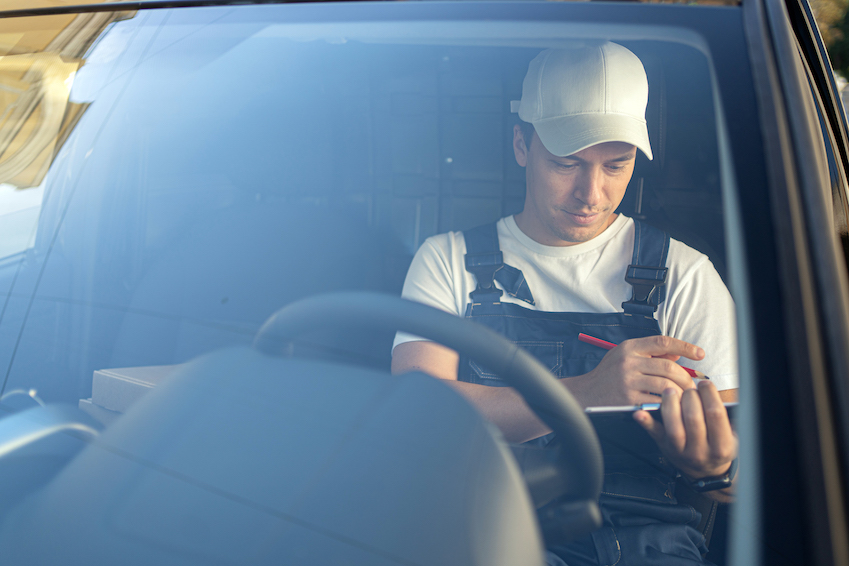 The driver of the courier service is sitting in the car